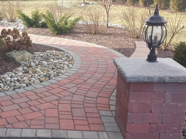 outdoor walkway with shrubs, rocks, mulch, and lights 