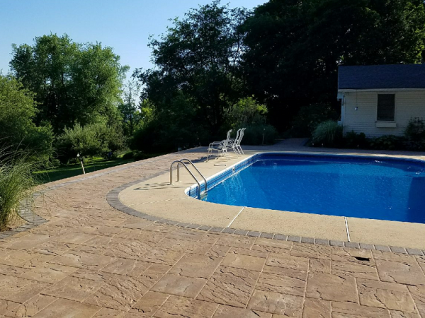 pool with custom hardscape, hottub, and waterfall in backyard