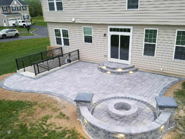 aerial view of backyard with custom hardscape, firepit and lighting 